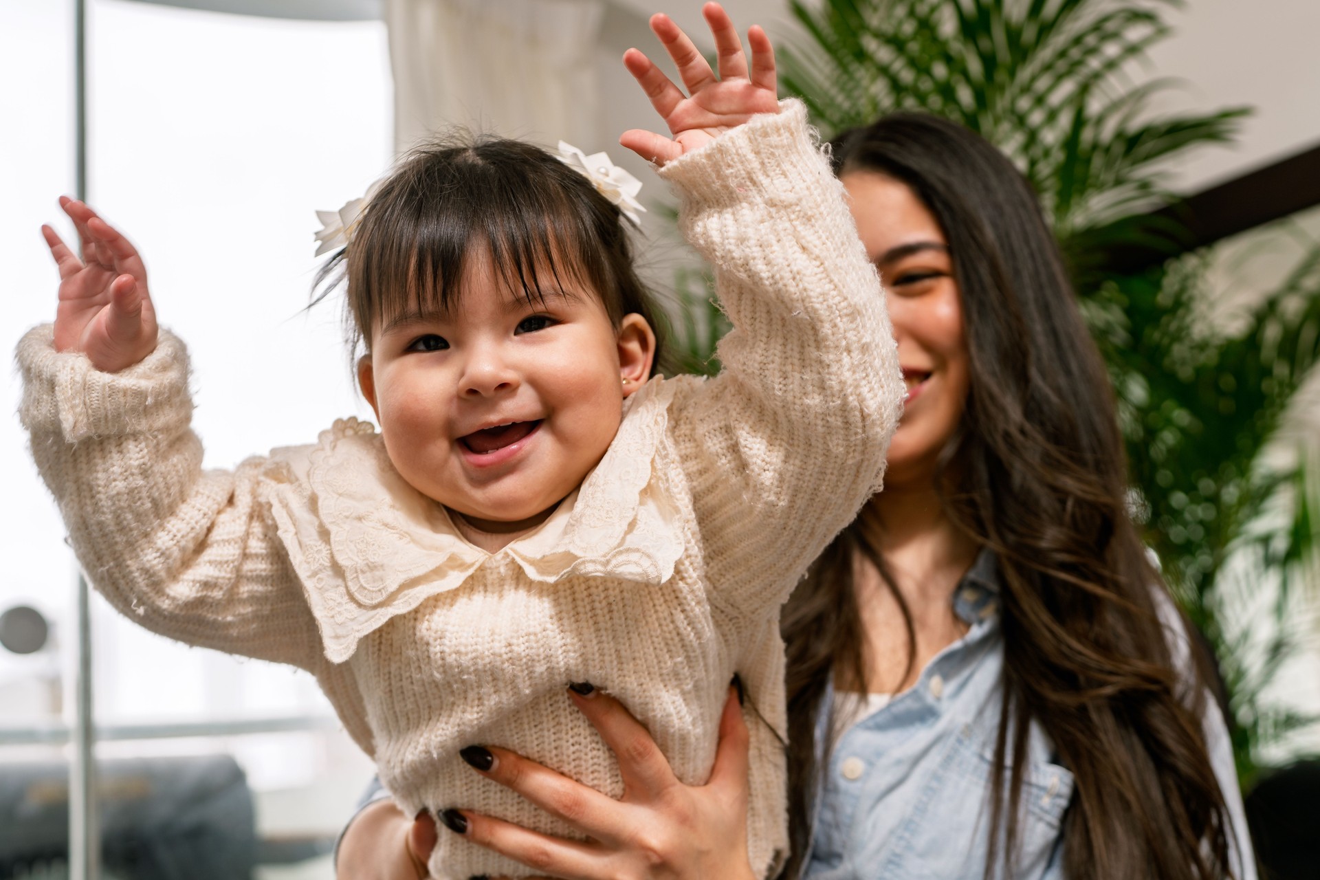 Young mother lifting her happy baby daughter at home
